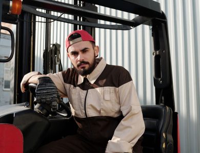 Focused forklift operator in uniform seated in industrial setting, showcasing work environment.