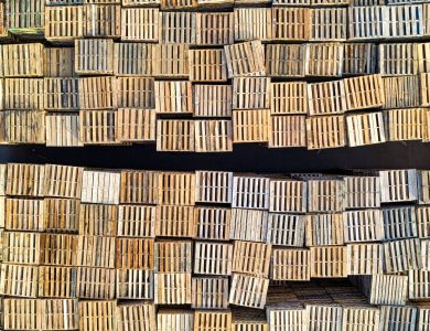 High angle shot of neatly stacked wooden pallets in an outdoor warehouse setting.