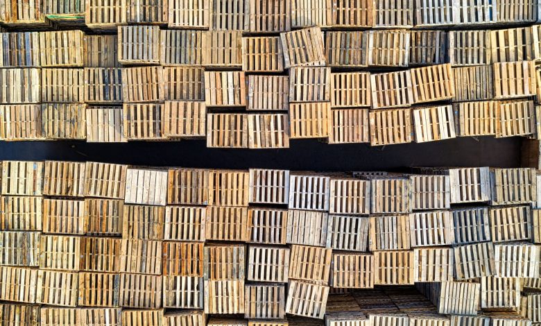 High angle shot of neatly stacked wooden pallets in an outdoor warehouse setting.
