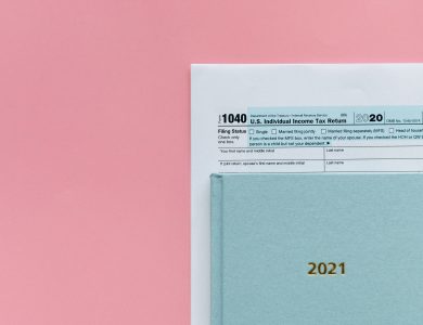U.S. 1040 tax form with 2021 planner on a pastel pink background, symbolizing tax season.