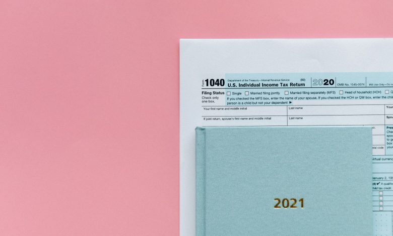 U.S. 1040 tax form with 2021 planner on a pastel pink background, symbolizing tax season.