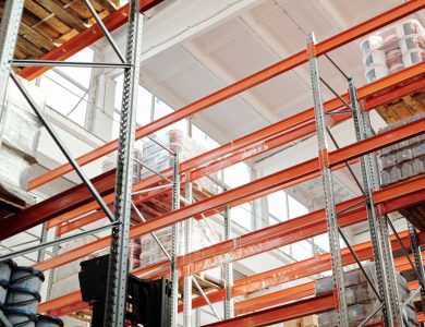 Bright warehouse interior with orange metal shelving units and stored goods.