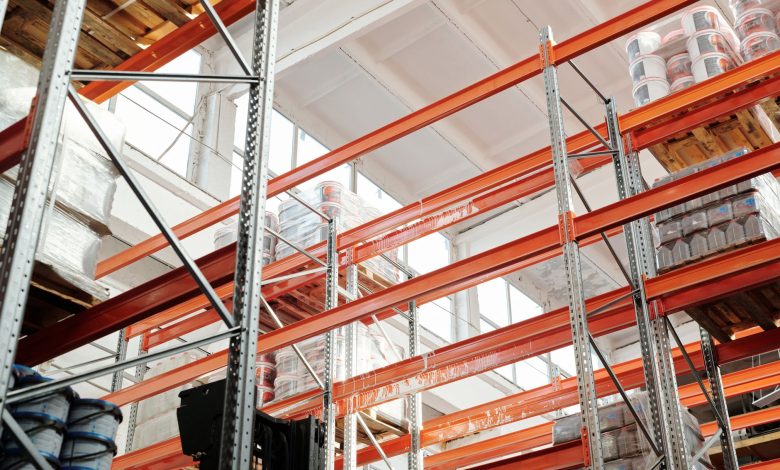 Bright warehouse interior with orange metal shelving units and stored goods.