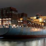 Night view of a cargo ship loaded with containers at Hamburg port, showcasing logistics and trade.
