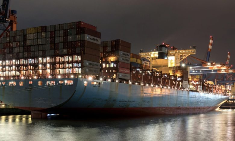 Night view of a cargo ship loaded with containers at Hamburg port, showcasing logistics and trade.