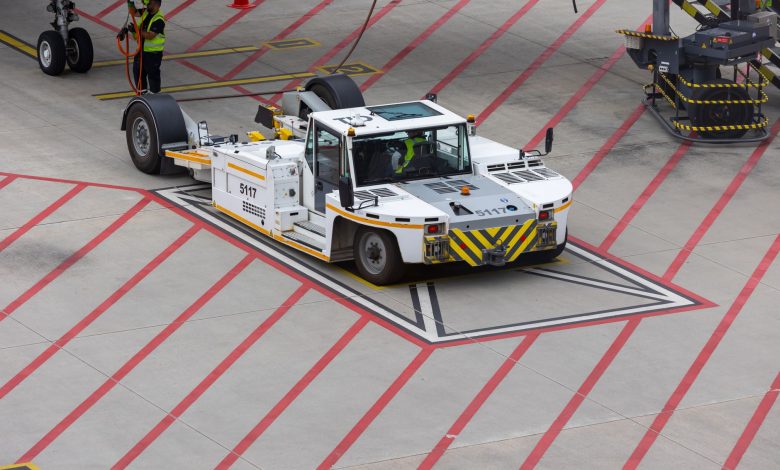 Aircraft tug maneuvering on a runway, preparing for plane departure at a busy airport.