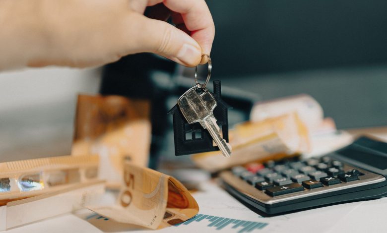 Close-up of a hand holding keys over euros and calculator, symbolizing real estate purchase.