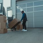 Courier unloading packages from a delivery van at a warehouse entrance. Efficient distribution.