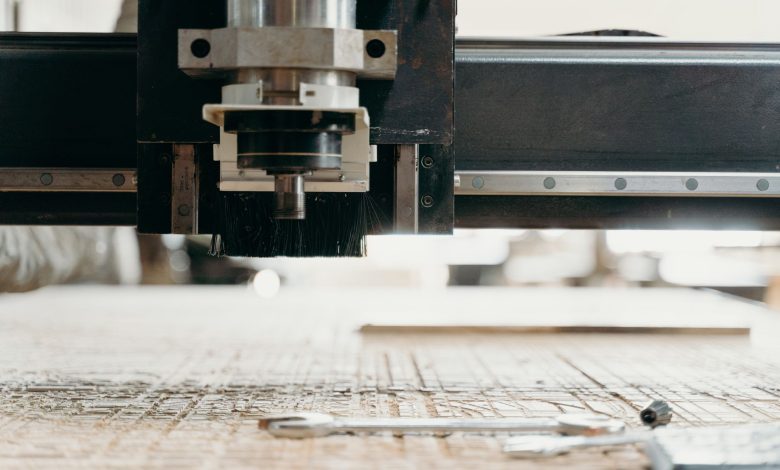 Close-up of a CNC machine carving a wooden surface indoors, showcasing precision equipment.