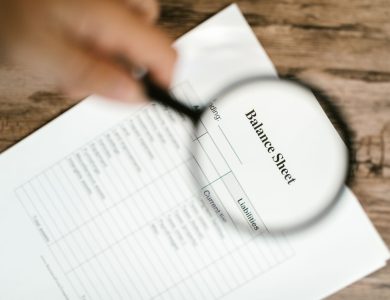 Close-up of a balance sheet under a magnifying glass on a wooden table.