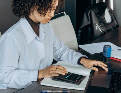 Young woman in office using a calculator for financial calculations.
