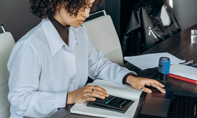 Young woman in office using a calculator for financial calculations.