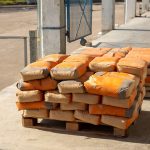 Pile of orange cement bags on a wooden pallet in an industrial setting.
