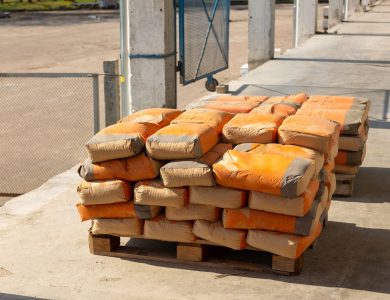 Pile of orange cement bags on a wooden pallet in an industrial setting.