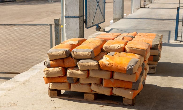 Pile of orange cement bags on a wooden pallet in an industrial setting.
